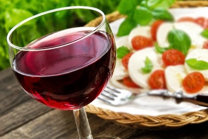 un bicchiere di vino rosso con sullo sfondo una pizza